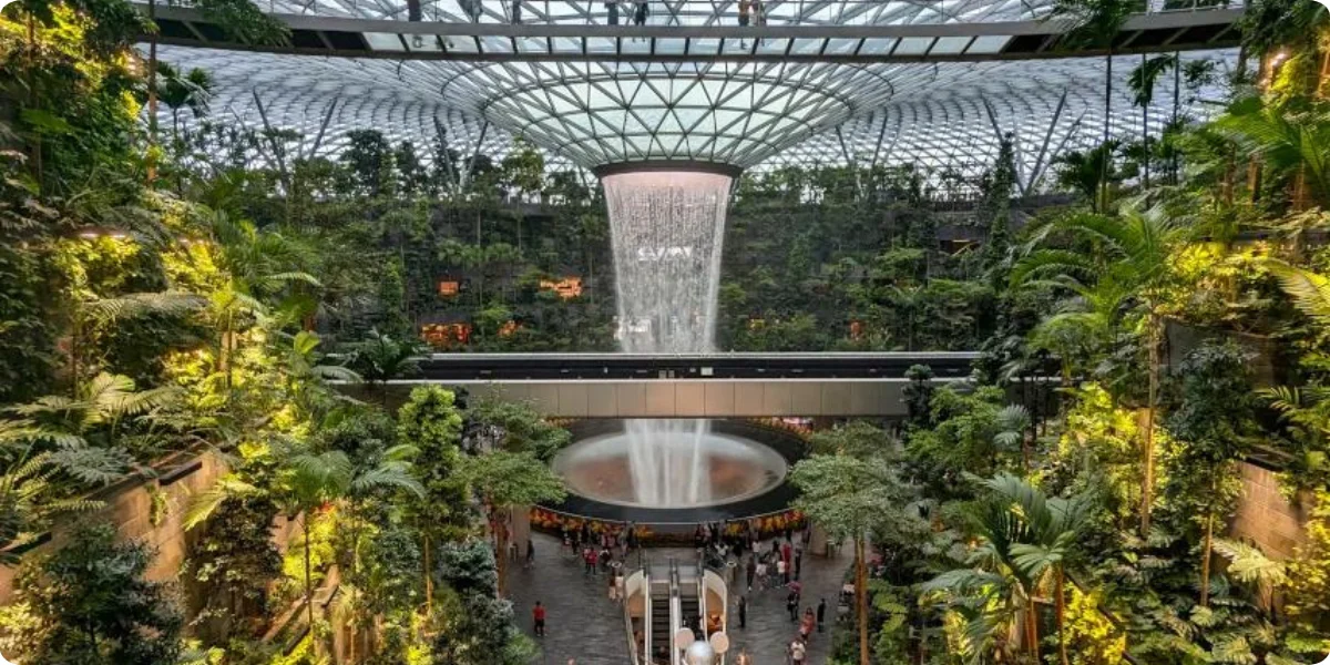 The atrium at Jewel Changi Airport features a stunning indoor waterfall surrounded by lush greenery and modern architecture.