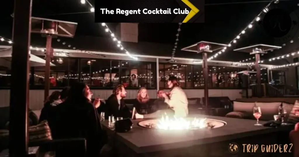 People sitting around a fire pit on the patio of The Regent Cocktail Club at night