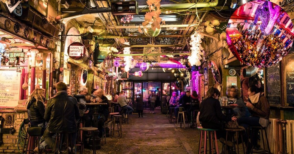 The lively interior of a ruin bar in Budapest, with colorful, eclectic decor, string lights, and people enjoying drinks and conversations.