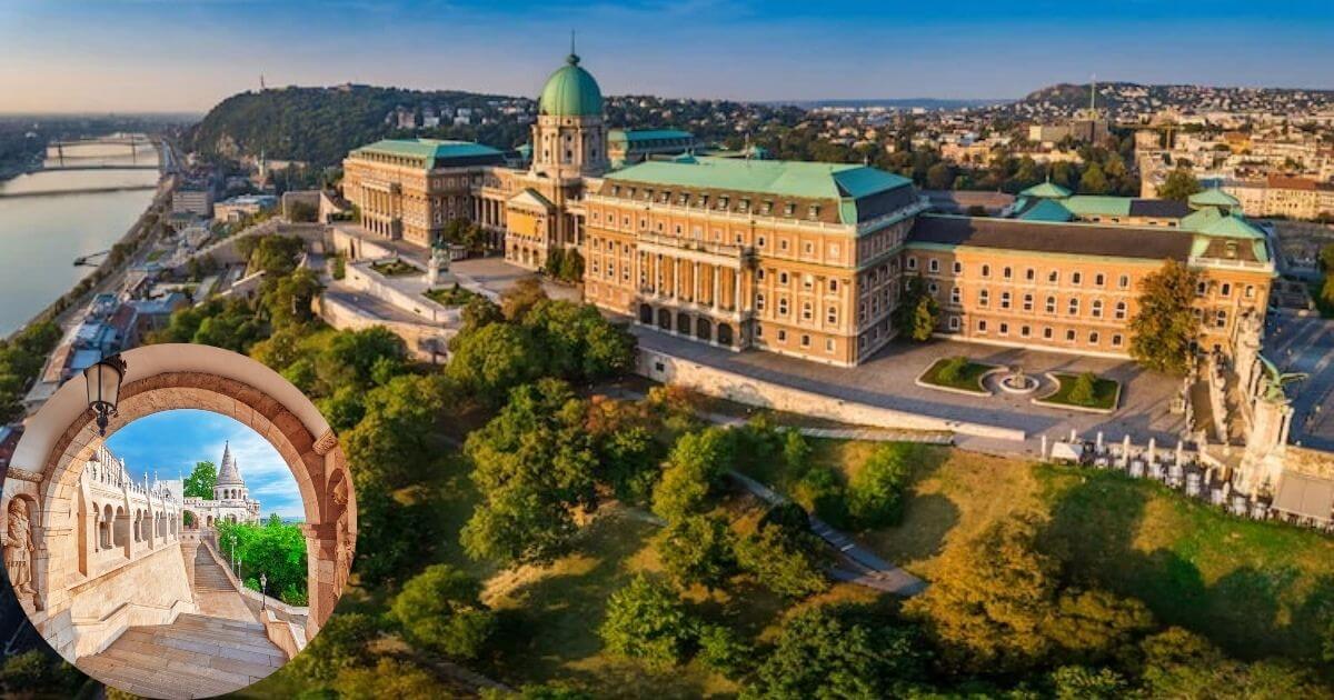 A panoramic view of Buda Castle and Castle Hill in Budapest, showing the historic buildings, a small, lush garden area, and the city in the distance under a blue sky.