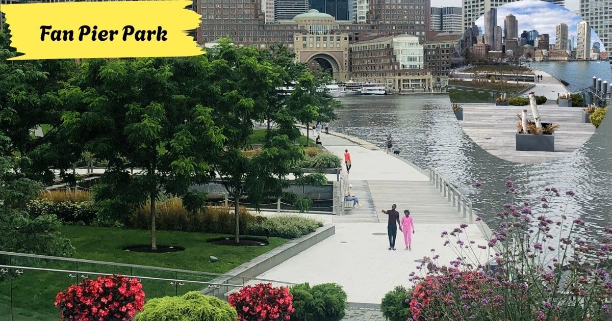People walking along the waterfront promenade at Fan Pier Park, with green lawns, trees, and the Boston skyline across the water.