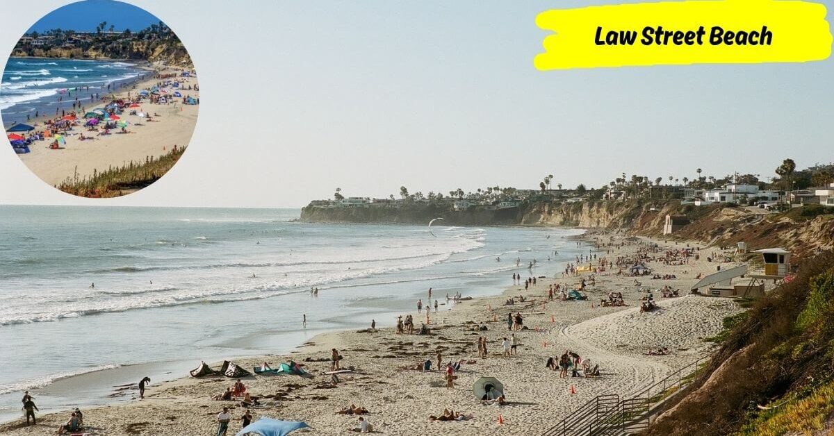 A wide view of Law Street Beach showing a sandy shoreline filled with people, with cliffs and a grassy area in the background, and an inset of an aerial view of the beach.