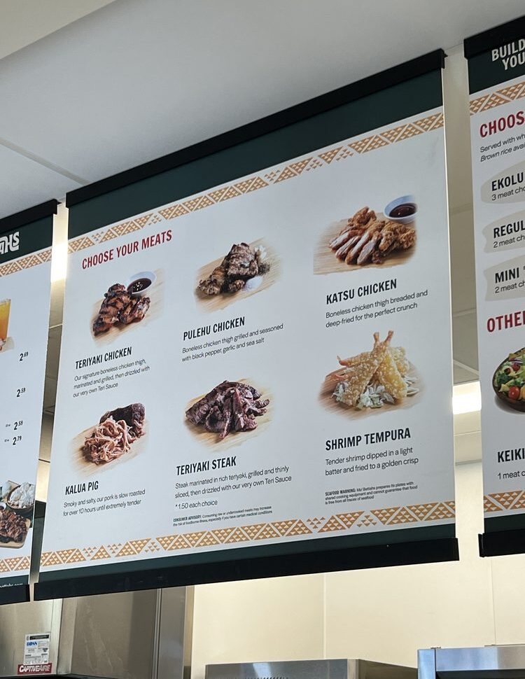 A shot of the overhead menu at a Mo' Bettahs restaurant, showing the "Choose Your Meats" section with pictures and descriptions for Teriyaki Chicken, Pulehu Chicken, Katsu Chicken, Kalua Pig, Teriyaki Steak, and Shrimp Tempura.
