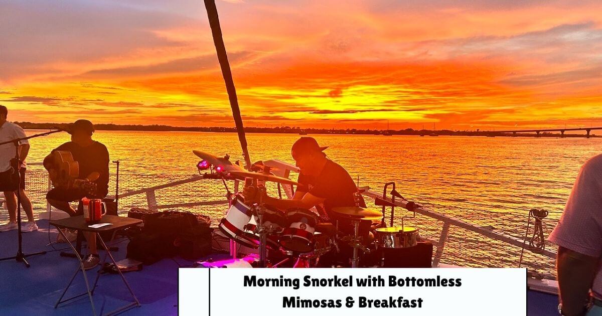 A live band playing music on a boat deck at sunset, with a golden and orange sky reflecting on the water.