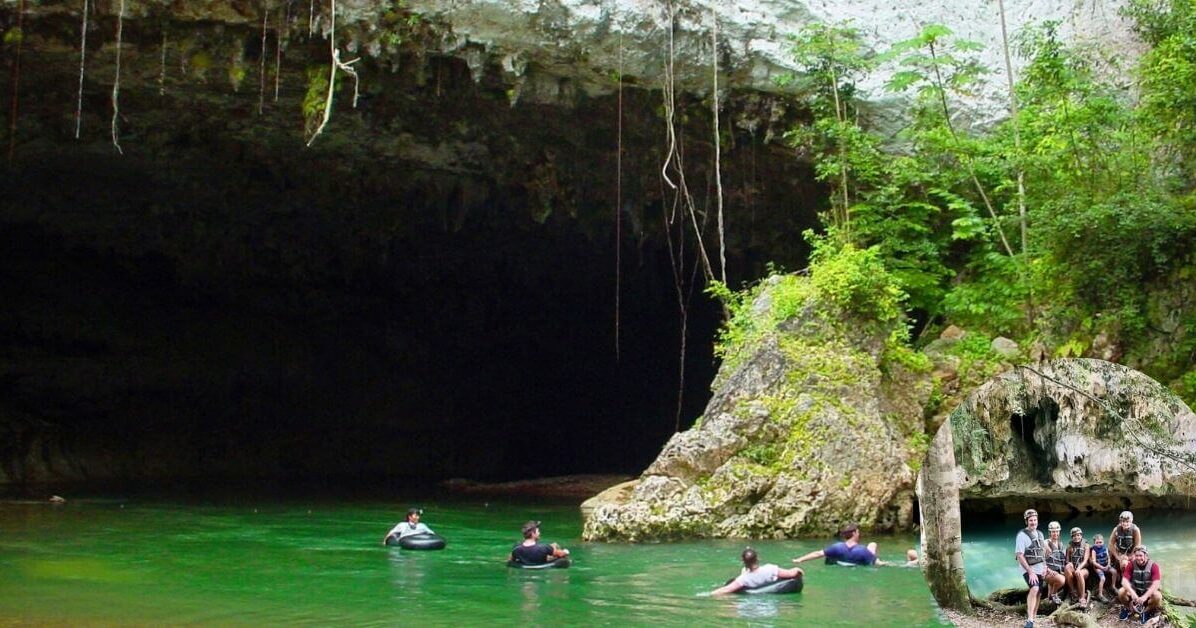 A person in an inner tube with a headlamp on, floating down a cave river at Nohoch Che’en Caves Branch Archaeological Reserve, with an inset showing an aerial view of the park.