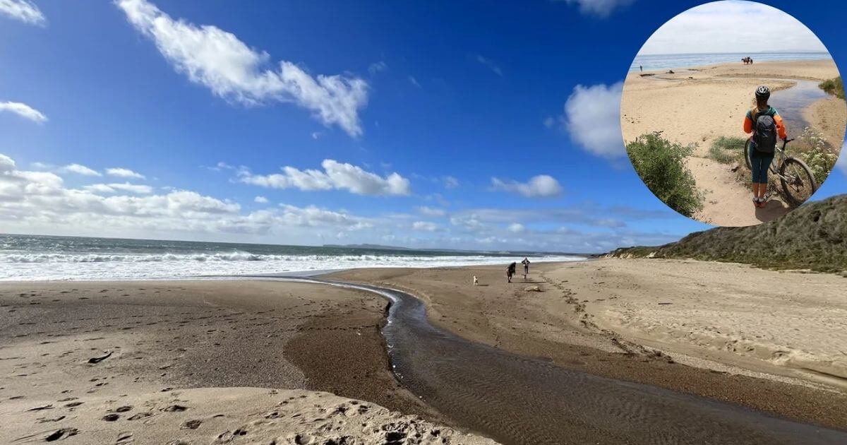 A wide shot of a scenic Santa Maria beach with waves crashing on the shore and a small stream running into the ocean. An inset shows a person with a bicycle hiking along a sandy path.