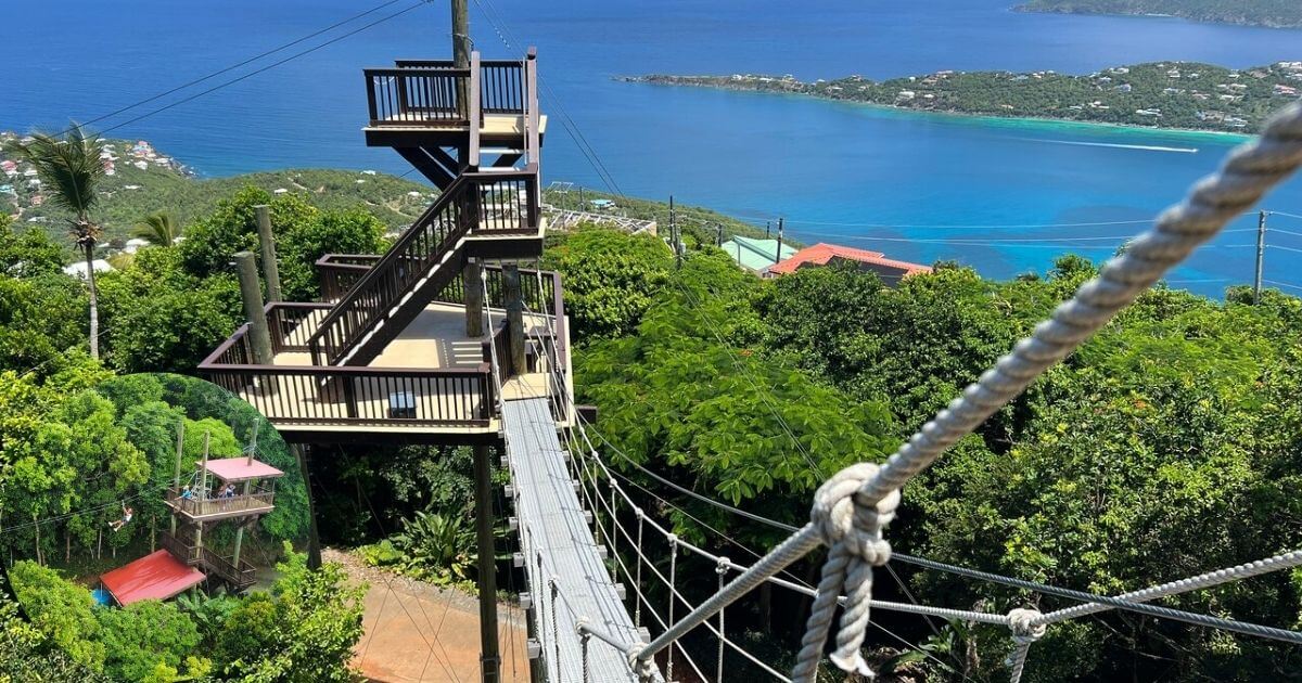 A zipline course and observation deck built high on a tropical mountain, with a view of the beautiful blue ocean in the distance. An inset shows a person ziplining through a lush green forest.