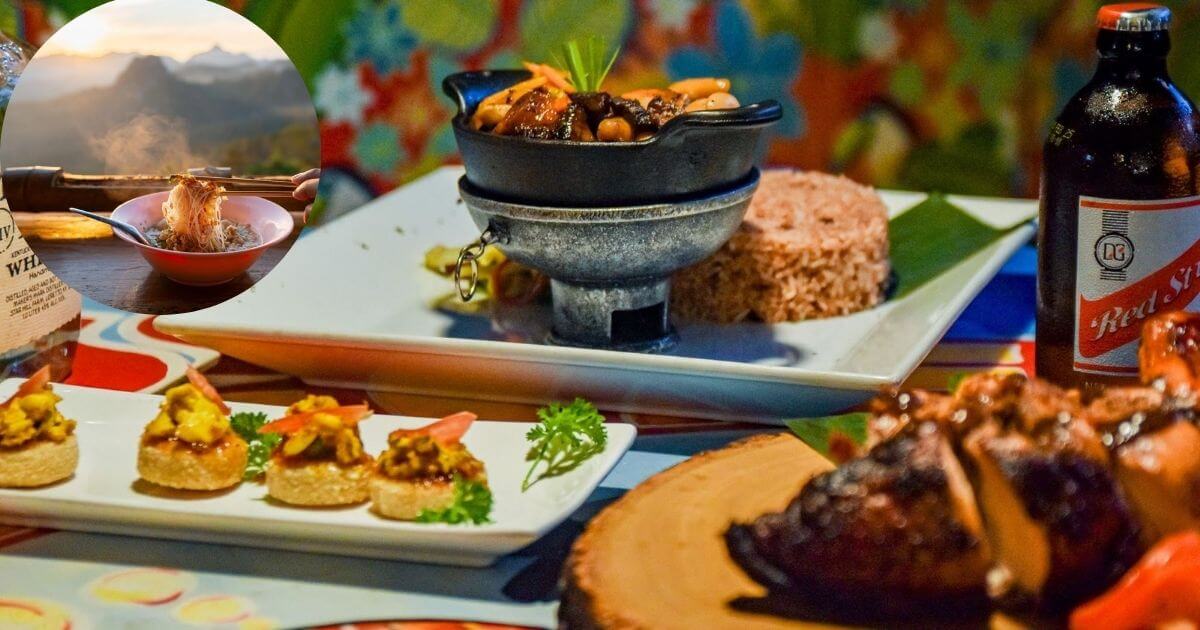 A table filled with a variety of colorful local dishes, including a stew in a black bowl, rice, appetizers, and a bottle of Red Stripe beer. An inset shows a plate of food on a table with a scenic mountain view in the background.