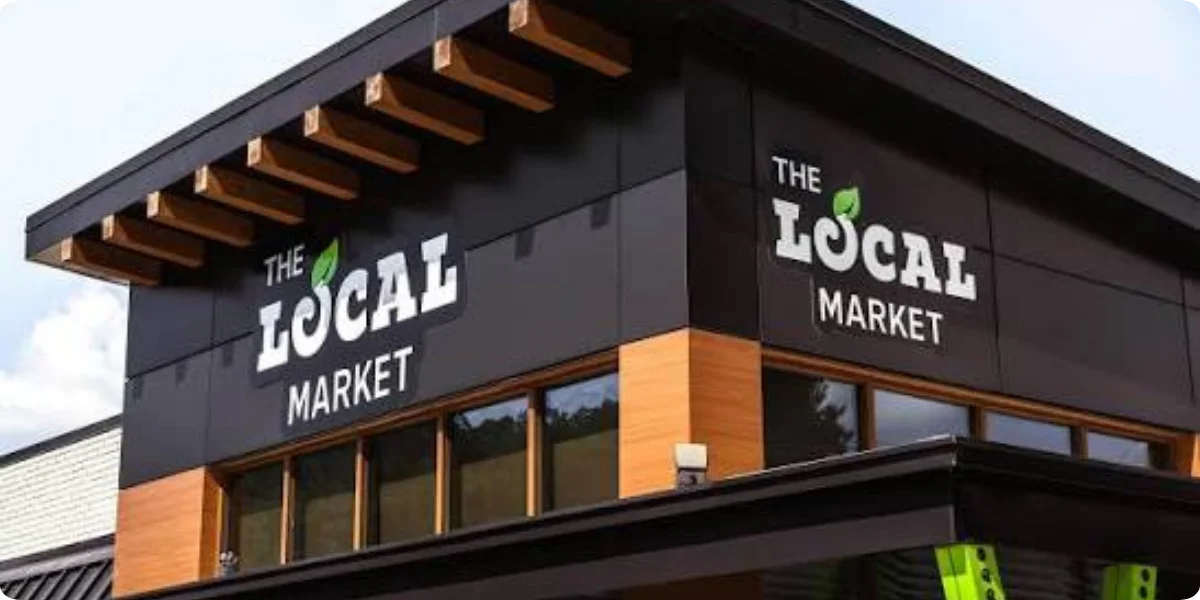 A grocery store exterior featuring a sign that reads "Local Market," showcasing a welcoming community atmosphere.