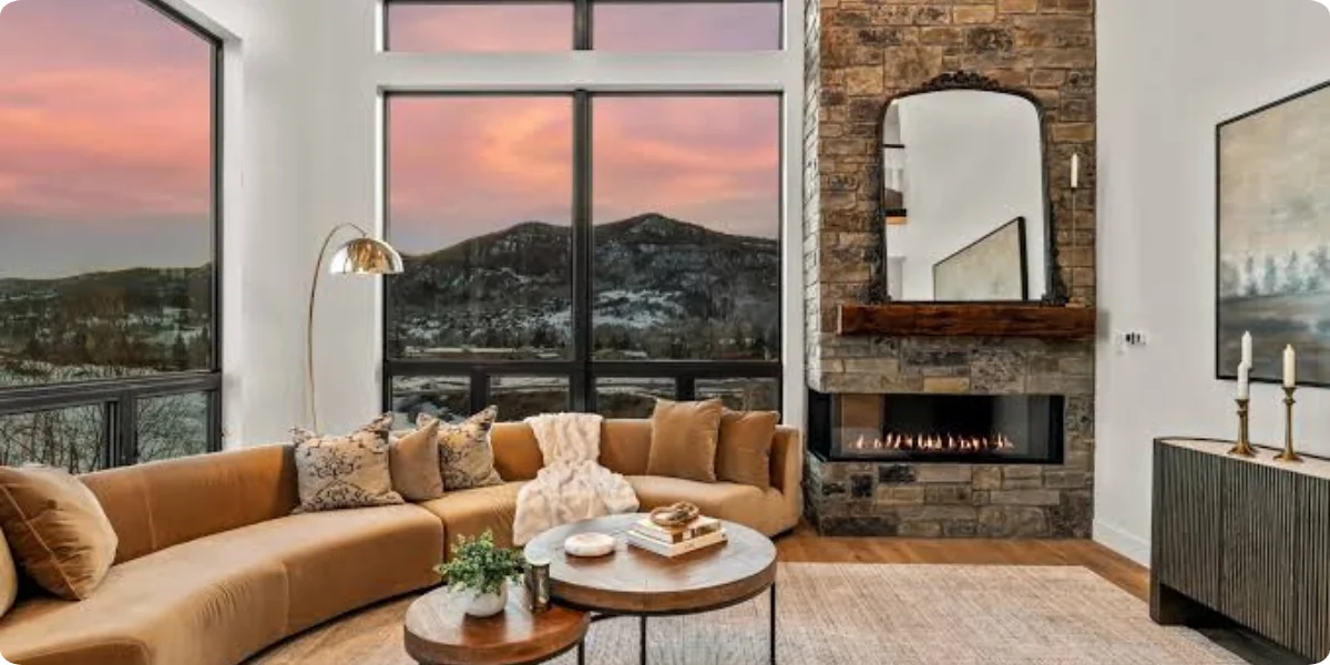 A cozy living room featuring a fireplace and large windows showcasing a stunning mountain view.