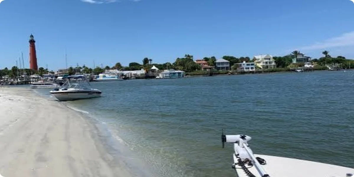 A boat rests on the beach beside a lighthouse, showcasing a scenic view of the island in Ponce.