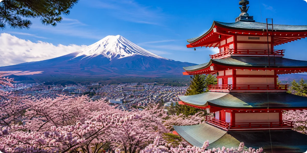 A traditional Japanese pagoda stands prominently with a mountain backdrop, showcasing cultural architecture and natural beauty.