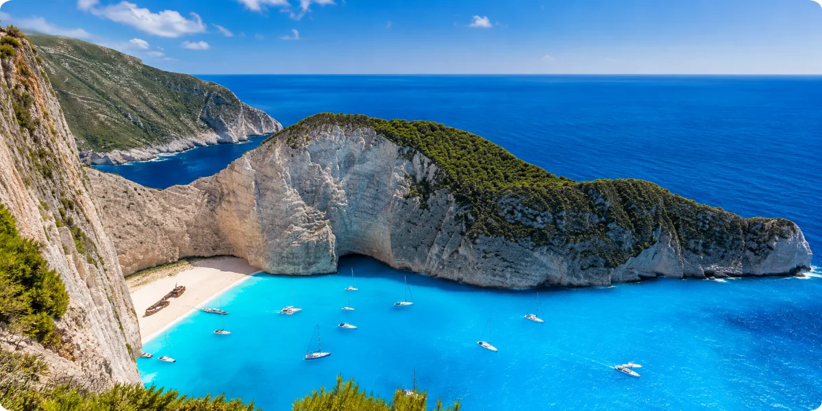A stunning beach in Zakynthos, showcasing vibrant water and boats gently bobbing in the waves.