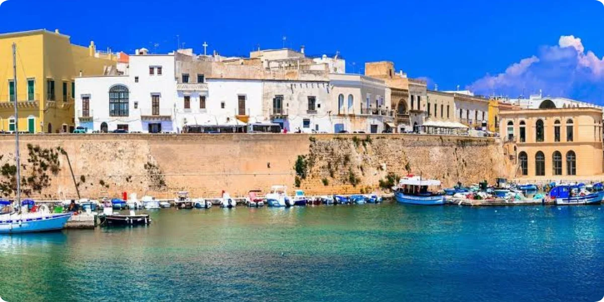 A scenic view of the port of Gallipoli, Italy, showcasing boats and the vibrant coastal landscape.