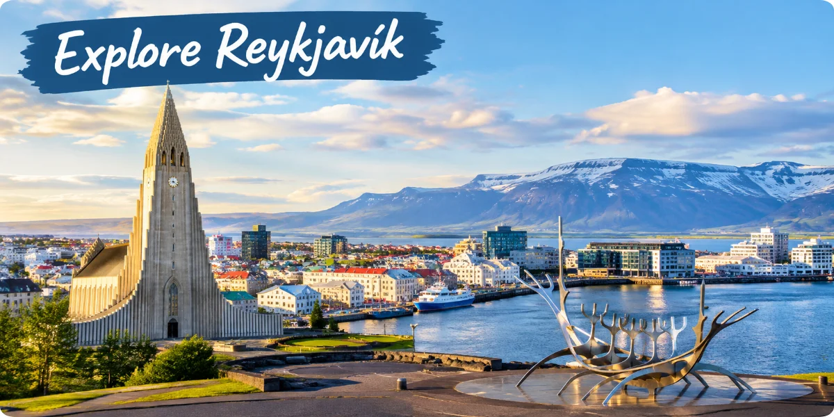 A panoramic view of Reykjavík showcasing colorful buildings, mountains, and the ocean under a clear blue sky.