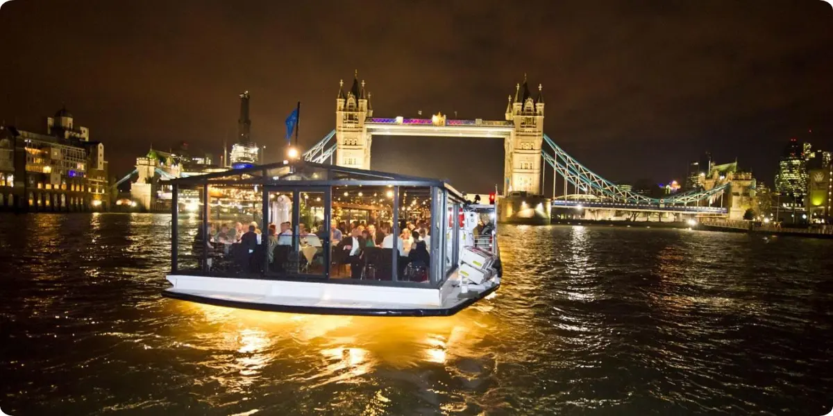 Evening River Thames cruise passing illuminated Tower Bridge in London