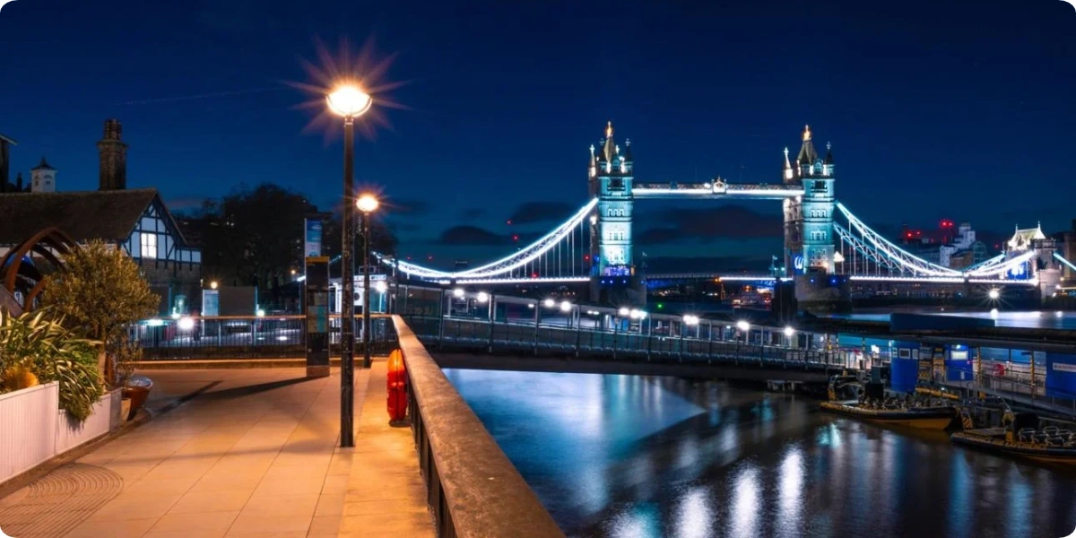 Tower Bridge and the illuminated River Thames viewed from a public walkway at night
