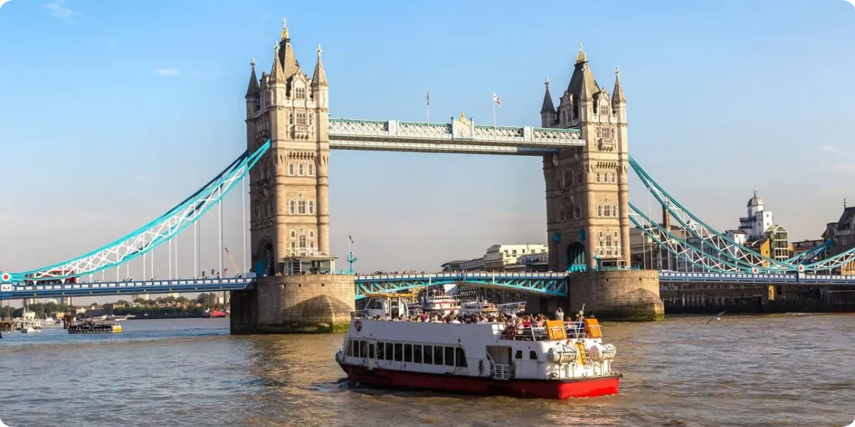 Sightseeing cruise boat passing Tower Bridge on the River Thames in London.